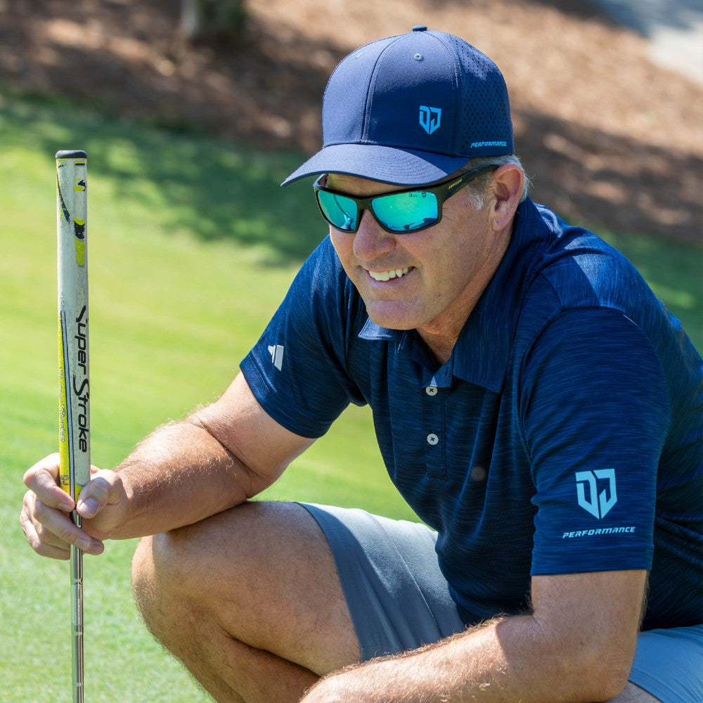 Dan Jansen smiling on the golf green while looking at the hole, wearing Jansen Eyewear