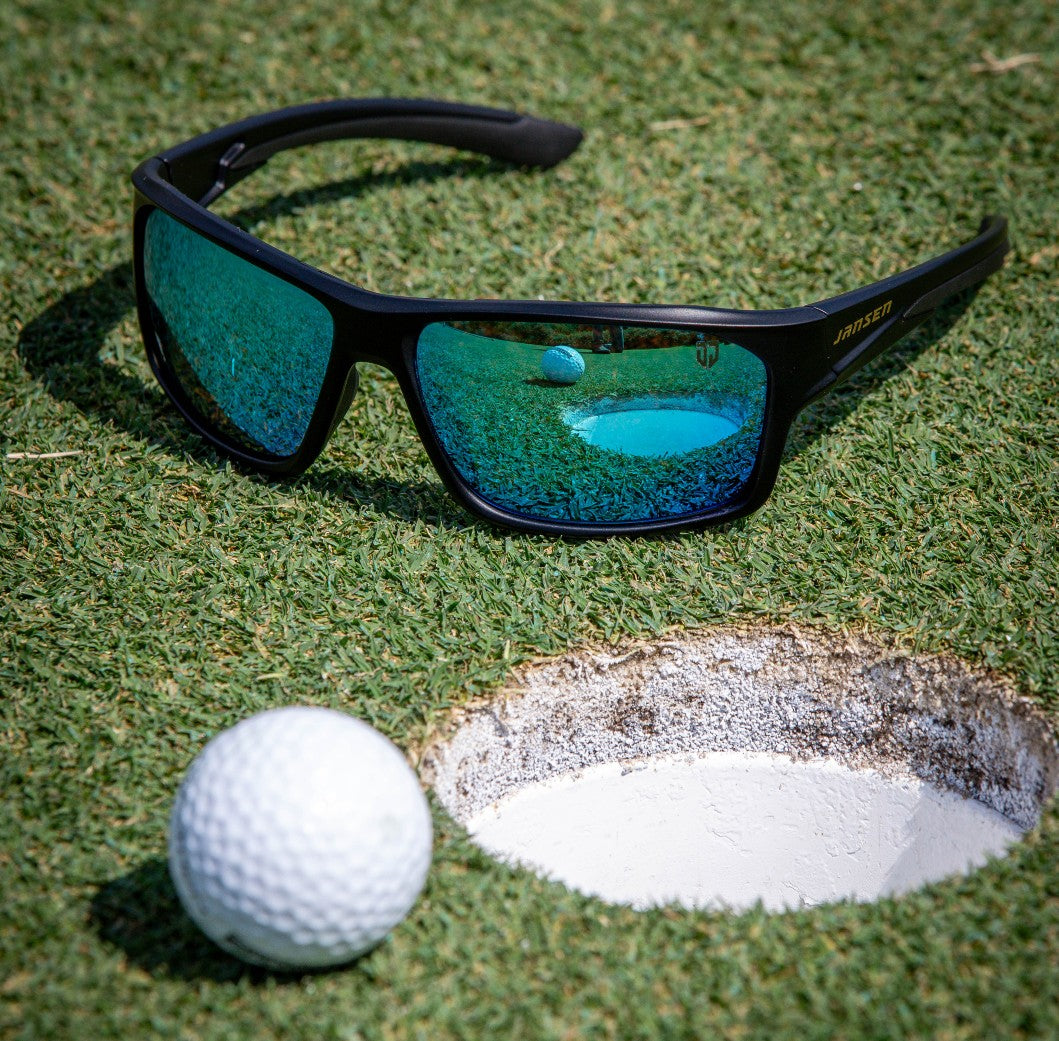 Golf ball near the hole beside Jansen sunglasses, symbolizing focus, clarity, and precision