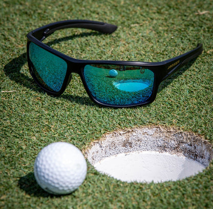 Golf ball near the hole beside Jansen sunglasses, symbolizing focus, clarity, and precision